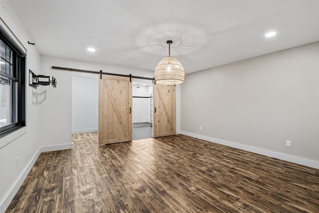 empty room with dark hardwood / wood-style flooring and a barn door