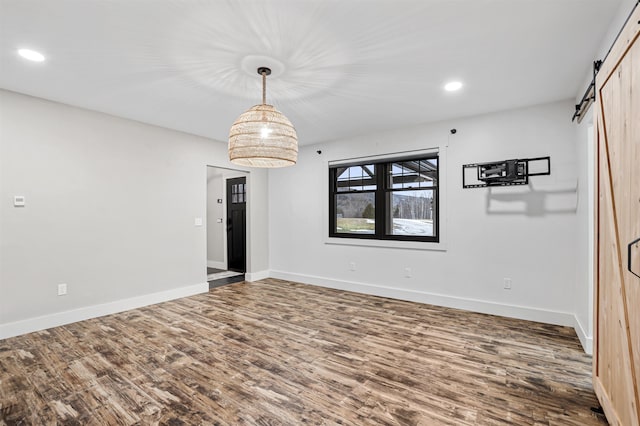 empty room with a barn door and wood-type flooring