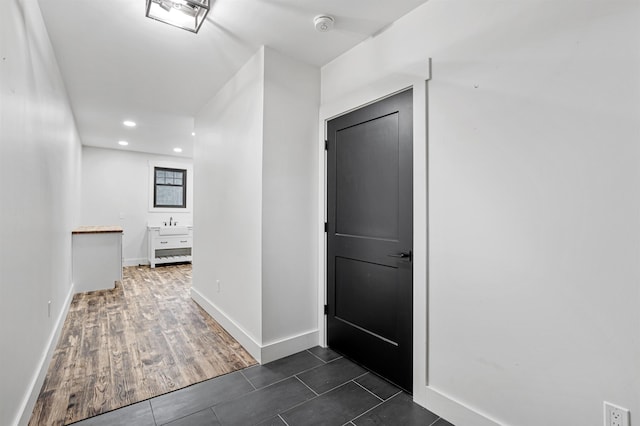 corridor with dark tile patterned flooring and sink