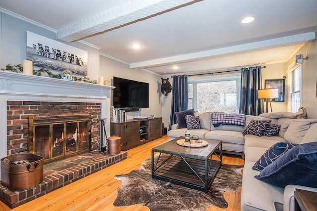 living room with beam ceiling, a fireplace, crown molding, and light hardwood / wood-style flooring