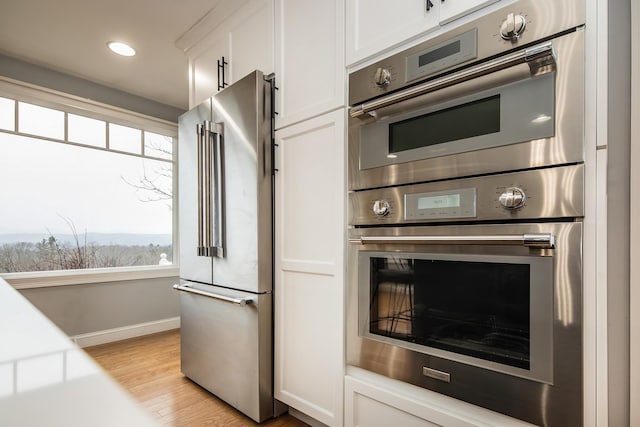 kitchen featuring appliances with stainless steel finishes, white cabinets, and light hardwood / wood-style flooring