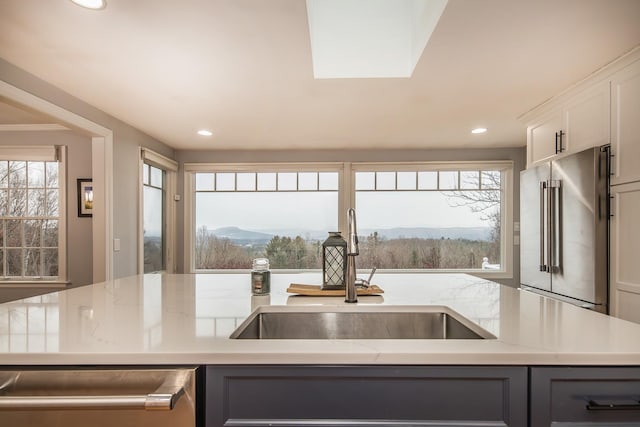 kitchen featuring sink, appliances with stainless steel finishes, white cabinetry, a wealth of natural light, and a mountain view