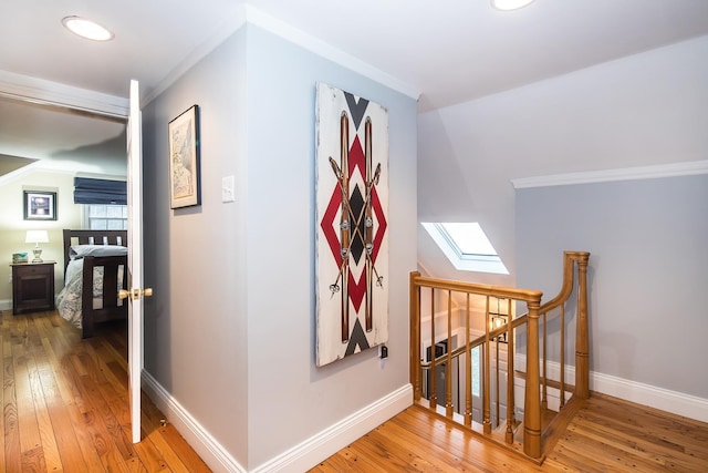 hallway with ornamental molding, a skylight, and hardwood / wood-style floors