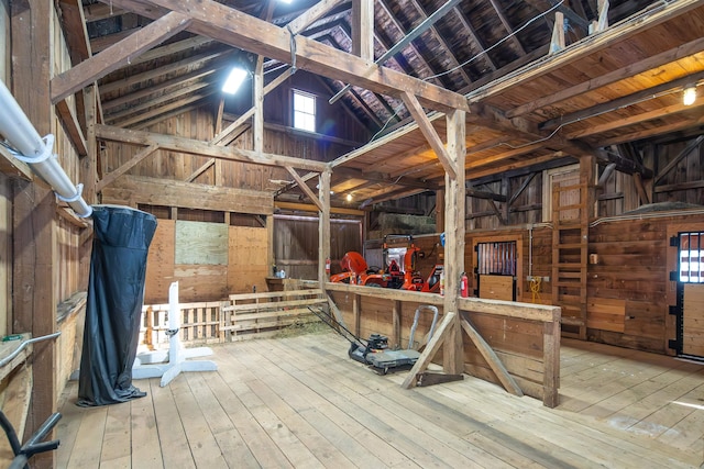 miscellaneous room featuring lofted ceiling, wood-type flooring, and wooden walls