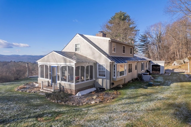 back of house featuring a yard, a mountain view, and a sunroom