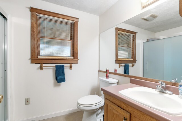 bathroom with a textured ceiling, vanity, toilet, and an enclosed shower