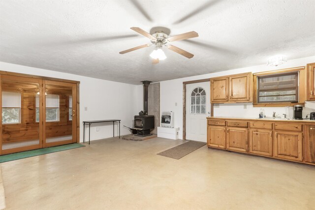 kitchen with a wood stove, ceiling fan, heating unit, and a textured ceiling