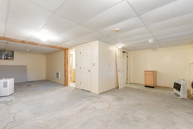 basement featuring a drop ceiling and heating unit