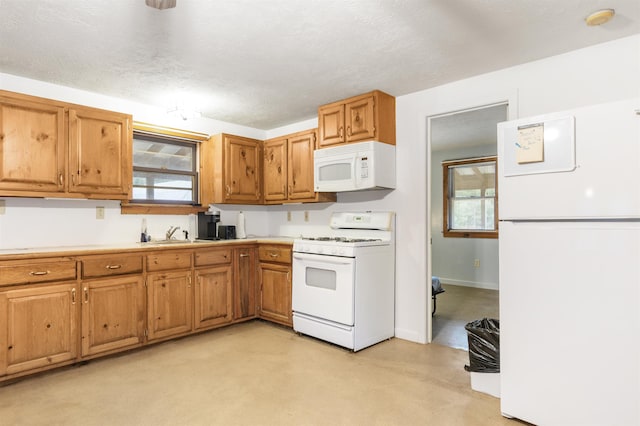 kitchen featuring a textured ceiling, plenty of natural light, white appliances, and sink