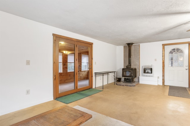 unfurnished living room with carpet, a textured ceiling, heating unit, and a wood stove