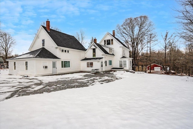 snow covered rear of property with an outbuilding and a garage