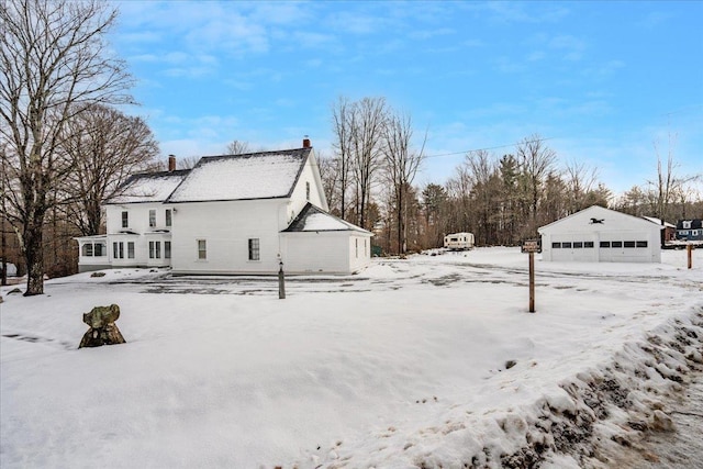 snow covered property featuring an outbuilding and a garage