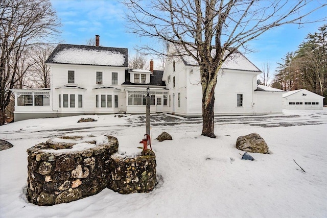 snow covered rear of property with a garage