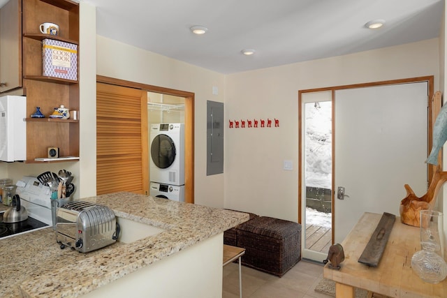 kitchen with light stone counters, light tile patterned floors, stacked washer / dryer, and electric panel