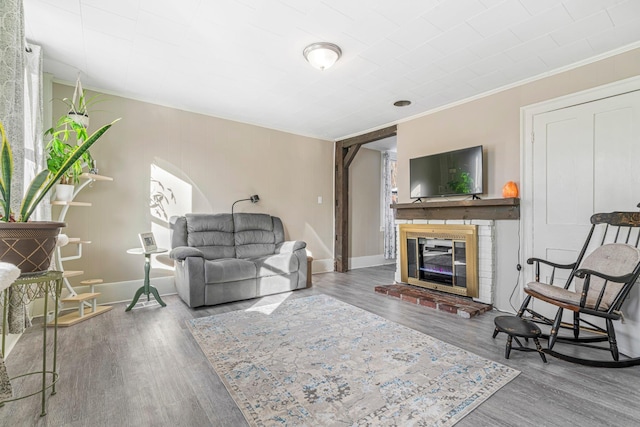 living room featuring hardwood / wood-style floors, crown molding, and a brick fireplace