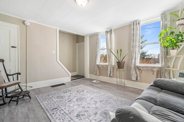 living area with hardwood / wood-style flooring, plenty of natural light, and crown molding