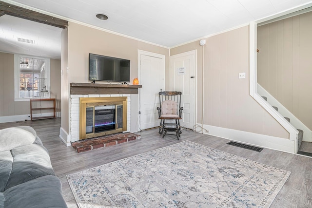 living room with a fireplace, ornamental molding, and hardwood / wood-style flooring