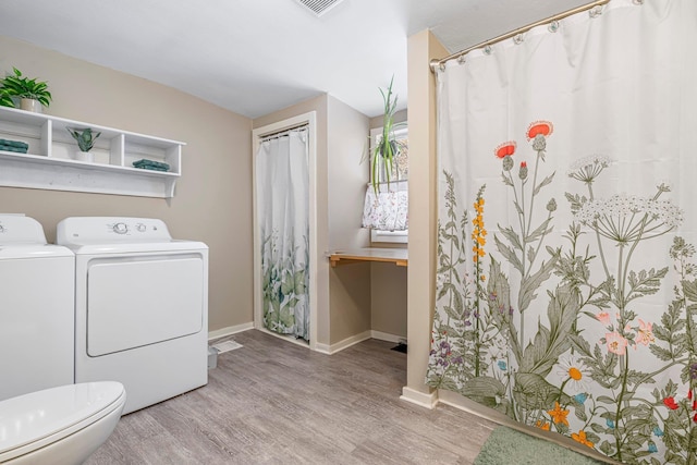 bathroom featuring washing machine and clothes dryer, hardwood / wood-style floors, and toilet