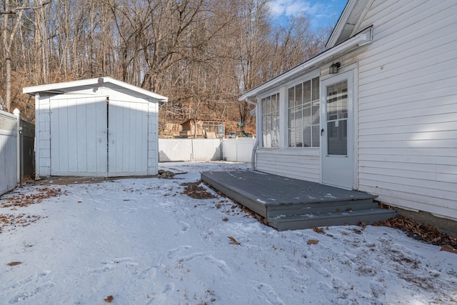 yard layered in snow featuring a shed and a deck