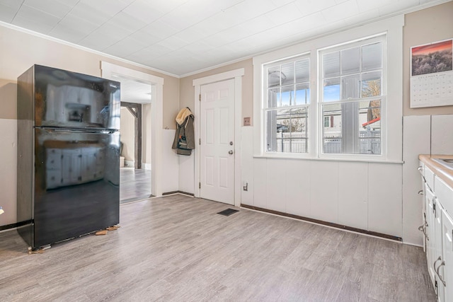 entryway with light hardwood / wood-style flooring and ornamental molding