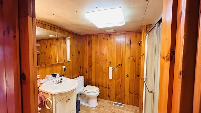 bathroom featuring hardwood / wood-style floors, vanity, toilet, and wooden walls