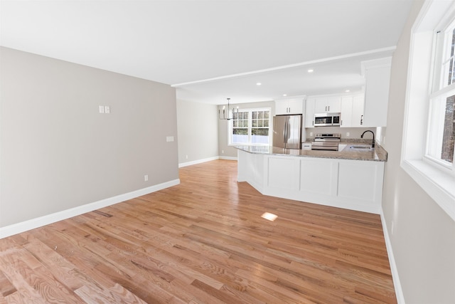 kitchen featuring white cabinetry, sink, stainless steel appliances, kitchen peninsula, and light wood-type flooring