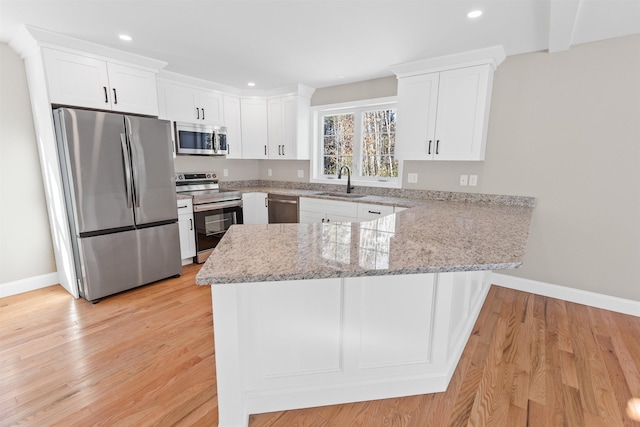 kitchen with kitchen peninsula, stainless steel appliances, white cabinetry, and sink