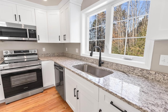 kitchen featuring white cabinets, light stone counters, sink, and appliances with stainless steel finishes