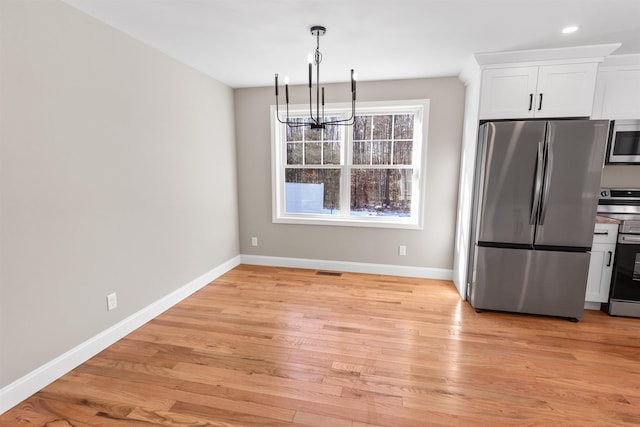 kitchen featuring stainless steel appliances, a chandelier, decorative light fixtures, white cabinets, and light wood-type flooring