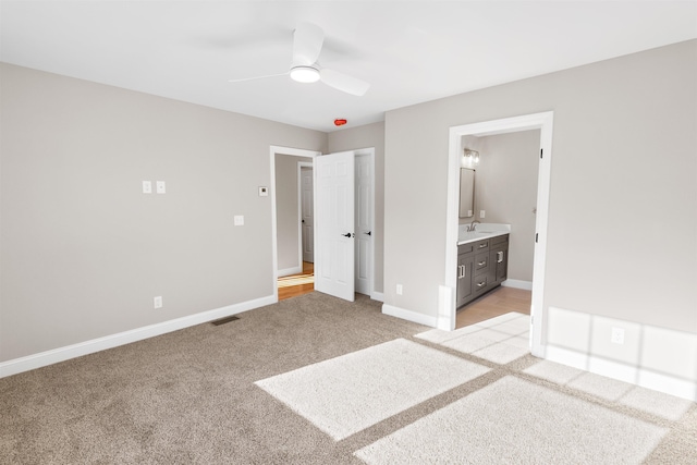 unfurnished bedroom with connected bathroom, light colored carpet, ceiling fan, and sink