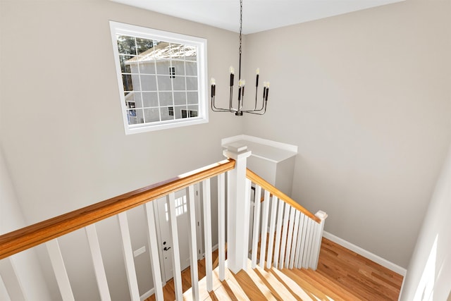 stairs with hardwood / wood-style flooring and a notable chandelier