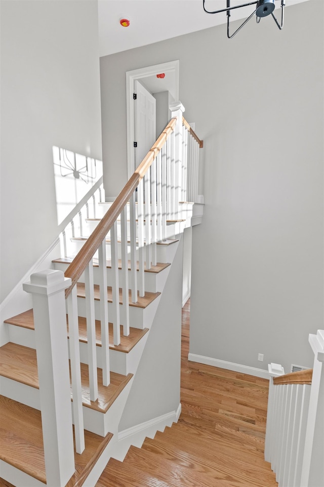 stairway featuring hardwood / wood-style floors and an inviting chandelier