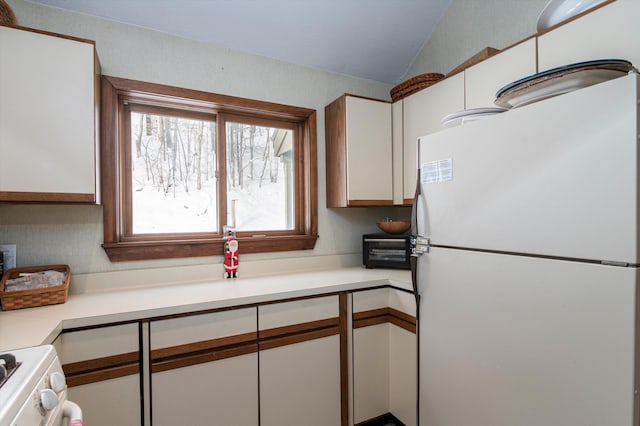 360 Okemo Trailside Ext Unit 37C, Ludlow, VT 05149 - kitchen with freestanding refrigerator, vaulted ceiling, stove, white cabinetry, and light countertops