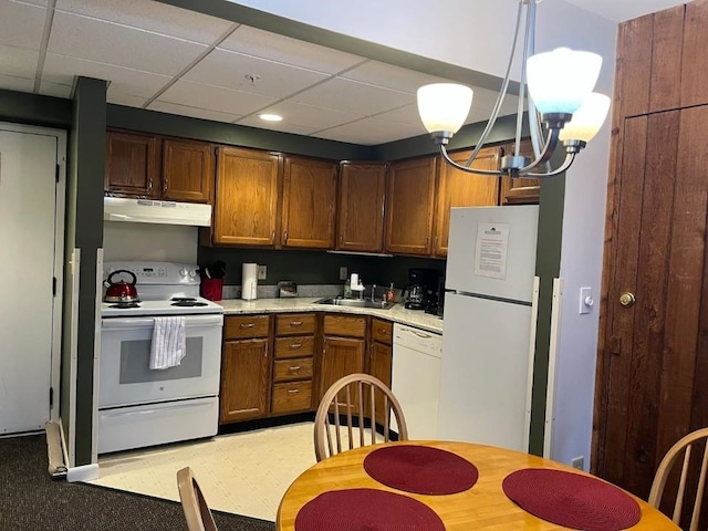 kitchen featuring white appliances, decorative light fixtures, a paneled ceiling, and sink