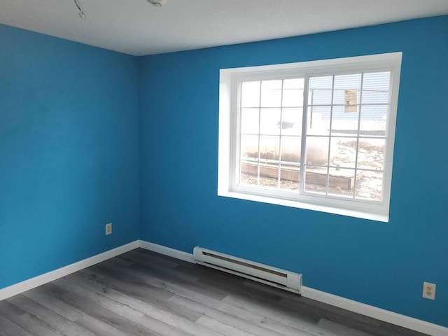 spare room featuring hardwood / wood-style flooring, a healthy amount of sunlight, and baseboard heating