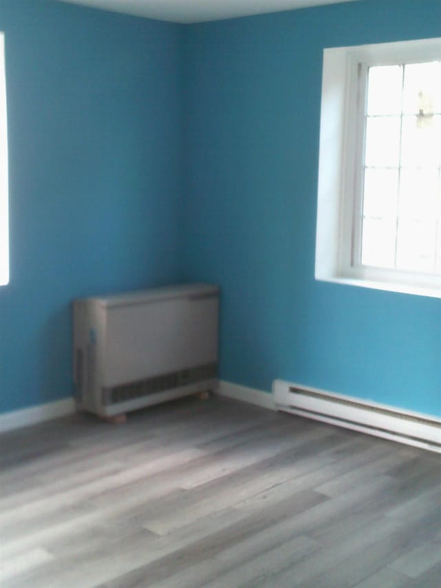 spare room featuring baseboard heating and light hardwood / wood-style flooring