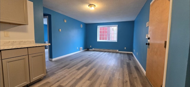 unfurnished dining area featuring light hardwood / wood-style floors, baseboard heating, and a textured ceiling