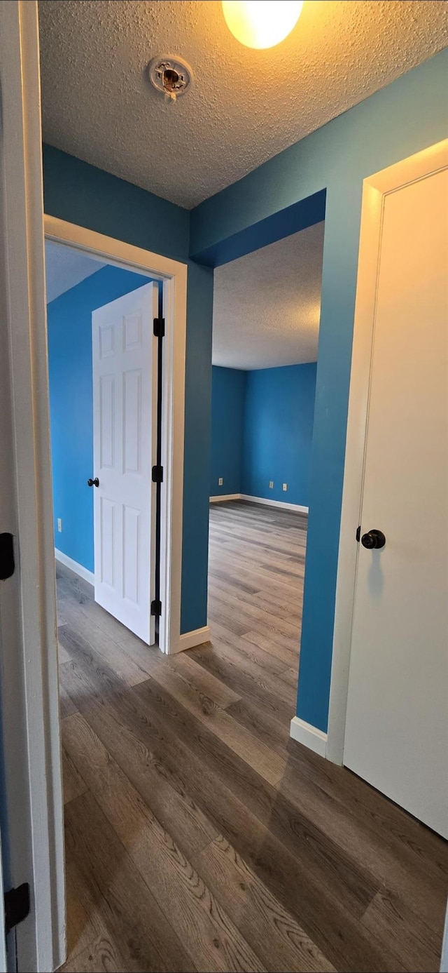 hall with dark hardwood / wood-style flooring and a textured ceiling