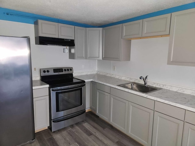 kitchen with appliances with stainless steel finishes, sink, gray cabinetry, a textured ceiling, and dark wood-type flooring