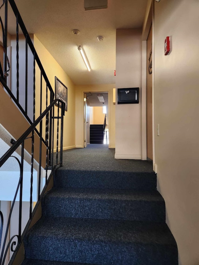 stairway featuring a textured ceiling