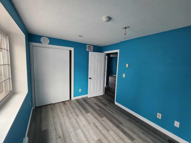 unfurnished bedroom with hardwood / wood-style flooring, a closet, and a textured ceiling