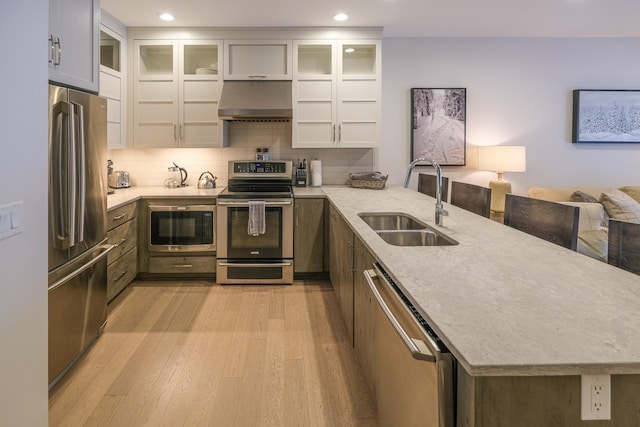 kitchen with wall chimney exhaust hood, sink, white cabinetry, light hardwood / wood-style flooring, and stainless steel appliances