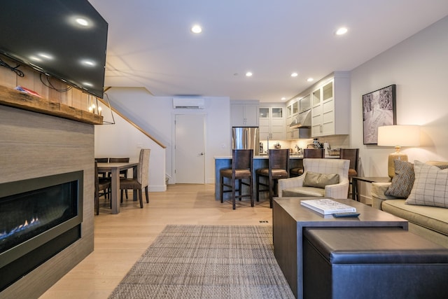 living room featuring light hardwood / wood-style flooring and a wall unit AC