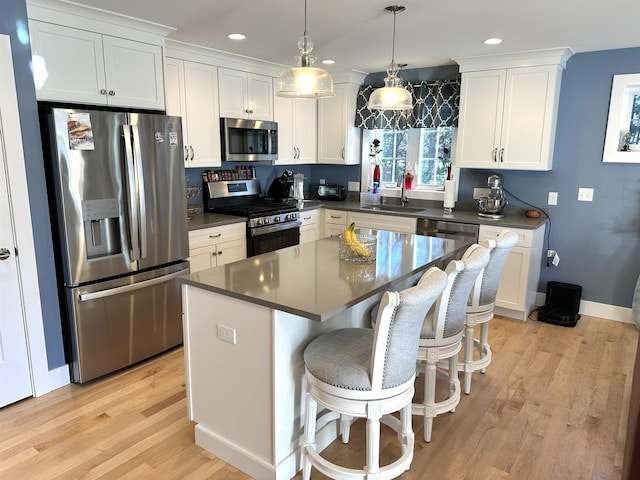 kitchen featuring white cabinets, hanging light fixtures, sink, appliances with stainless steel finishes, and a kitchen island