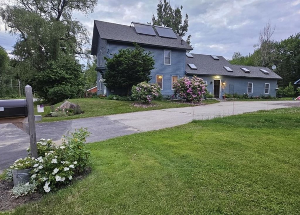 view of front facade featuring solar panels and a front lawn