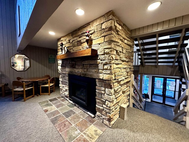 living area with a stone fireplace, recessed lighting, and wooden walls