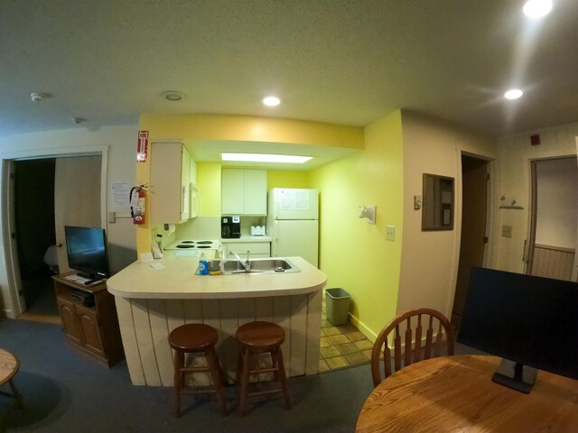 kitchen with white appliances, a peninsula, recessed lighting, a sink, and light countertops