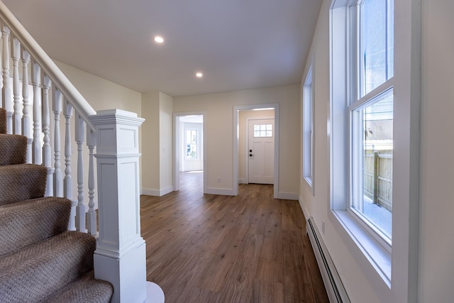 entrance foyer with a baseboard radiator, a wealth of natural light, and dark wood-type flooring