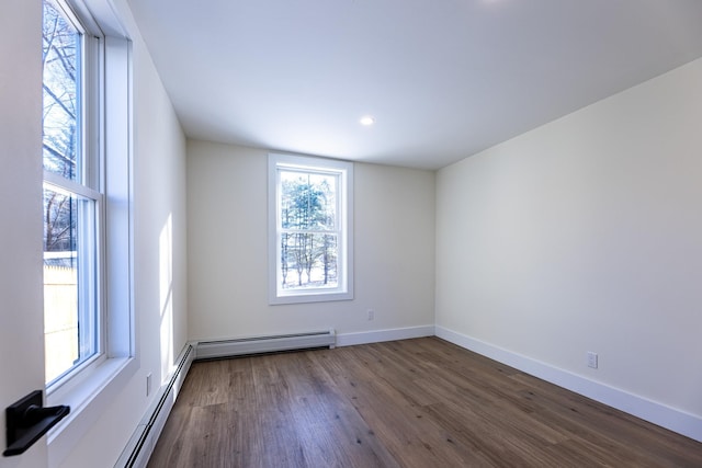 unfurnished room featuring baseboard heating and dark wood-type flooring