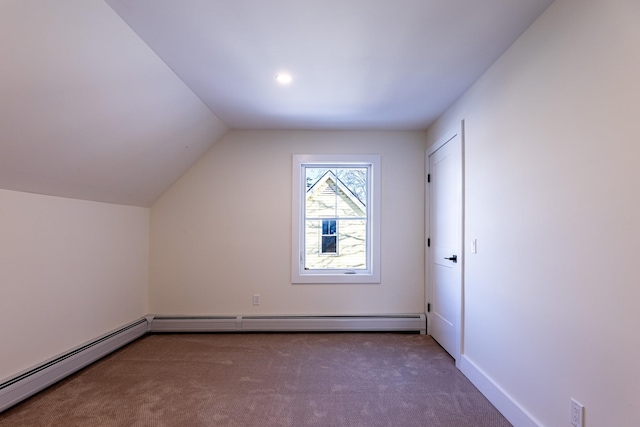 additional living space featuring dark colored carpet, baseboard heating, and lofted ceiling